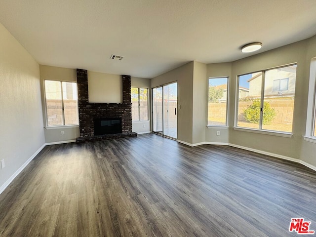 unfurnished living room with a brick fireplace and dark hardwood / wood-style flooring