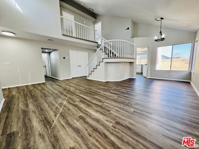 unfurnished living room featuring high vaulted ceiling and dark wood-type flooring