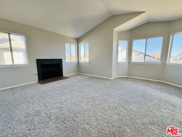 unfurnished living room featuring carpet, vaulted ceiling, and plenty of natural light