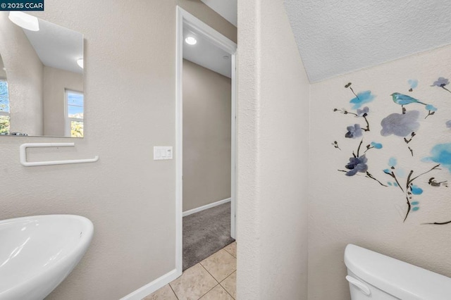 bathroom with toilet, vaulted ceiling, tile patterned flooring, a textured ceiling, and sink