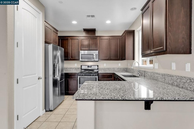 kitchen featuring light stone countertops, stainless steel appliances, kitchen peninsula, and sink