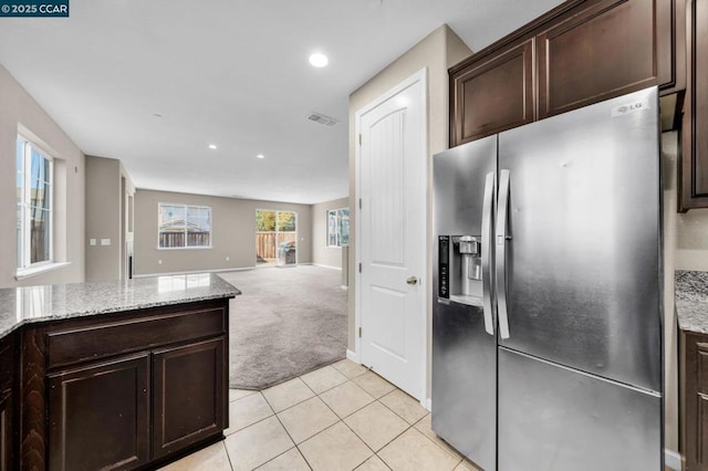 kitchen with light carpet, stainless steel refrigerator with ice dispenser, light stone counters, and dark brown cabinetry