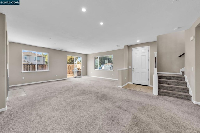 unfurnished living room with light colored carpet and a wealth of natural light