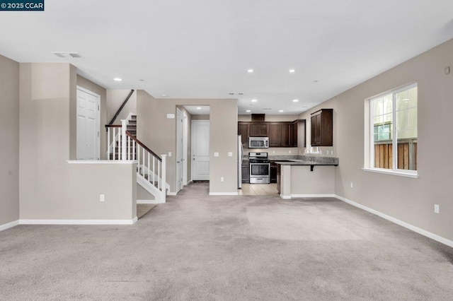 kitchen with light carpet, a breakfast bar area, appliances with stainless steel finishes, dark brown cabinetry, and sink