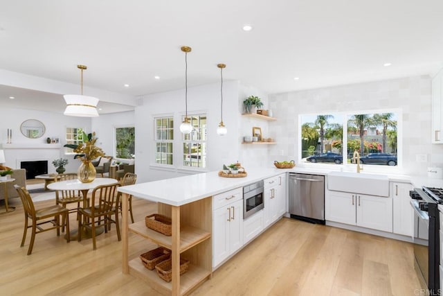 kitchen with stainless steel appliances, a sink, a peninsula, and open shelves