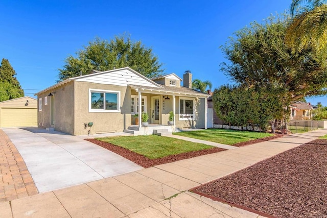 bungalow-style home featuring a porch, an outdoor structure, fence, stucco siding, and a front yard