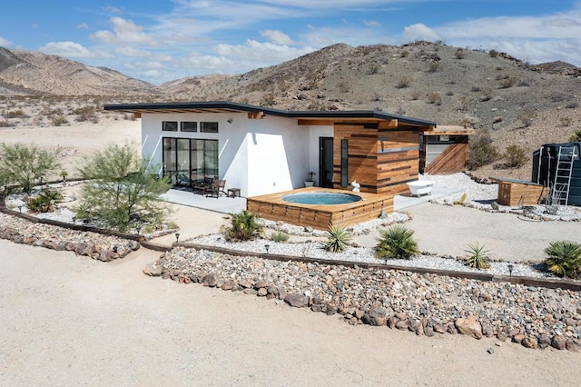 back of house featuring a mountain view, a patio, and an outdoor hot tub