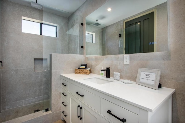 bathroom with tile walls, vanity, and a tile shower