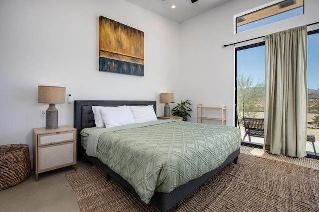 bedroom featuring multiple windows, access to outside, and concrete flooring