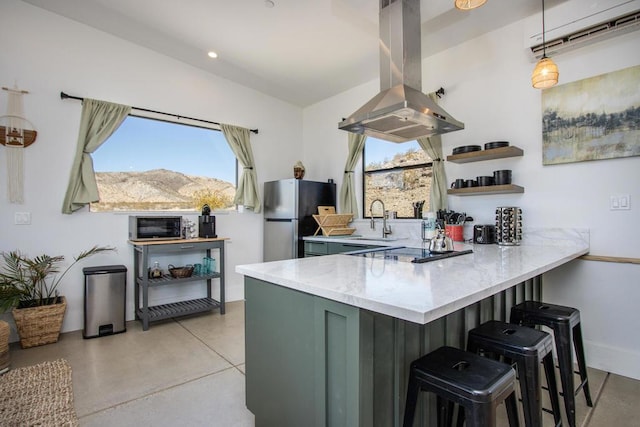 kitchen with island exhaust hood, a mountain view, stainless steel refrigerator, hanging light fixtures, and green cabinetry