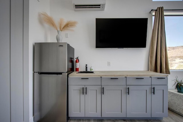 interior details featuring sink, hardwood / wood-style floors, stainless steel fridge, and a wall mounted air conditioner