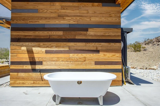 bathroom featuring concrete floors, a washtub, and wood walls