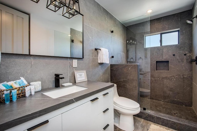 bathroom featuring toilet, tile walls, tiled shower, and vanity