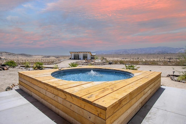 pool at dusk featuring an outbuilding and a mountain view