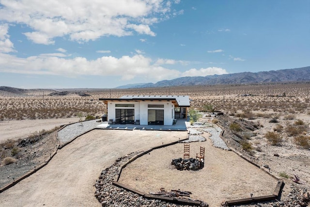 back of property with a mountain view and a patio area