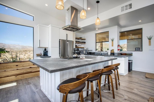 kitchen featuring white cabinetry, appliances with stainless steel finishes, a center island, and island range hood