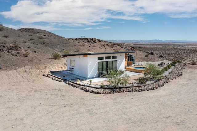 rear view of house with a patio area, a mountain view, and a hot tub