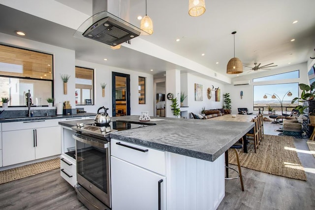 kitchen with a kitchen island, a kitchen bar, white cabinetry, hanging light fixtures, and stainless steel range with electric stovetop