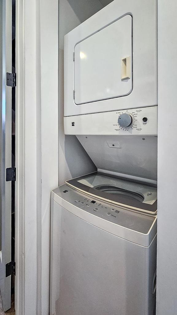 clothes washing area with stacked washing maching and dryer