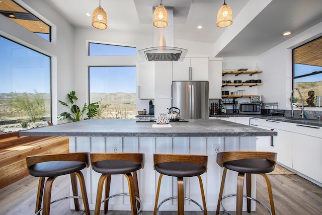 kitchen featuring decorative light fixtures, white cabinets, light wood-type flooring, and stainless steel refrigerator