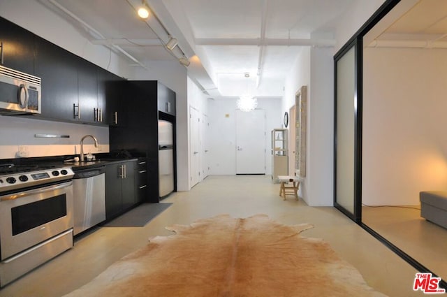 kitchen featuring track lighting, stainless steel appliances, pendant lighting, and sink