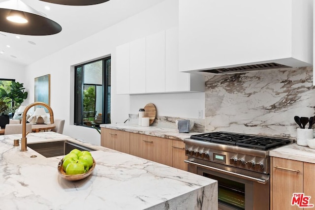 kitchen featuring white cabinetry, light stone countertops, sink, and stainless steel stove