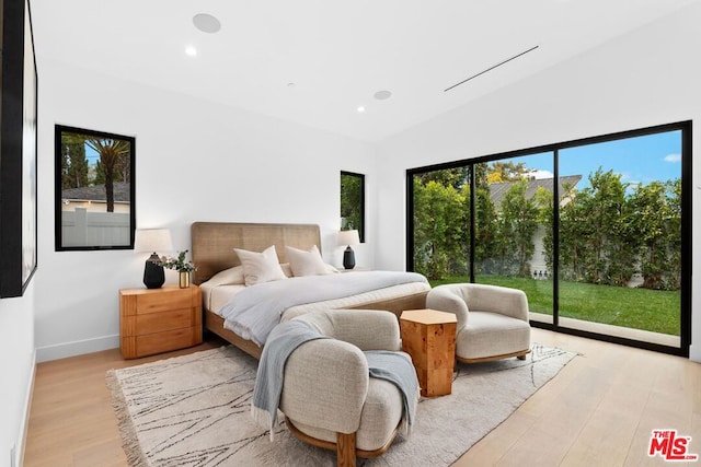 bedroom featuring light hardwood / wood-style flooring, vaulted ceiling, and access to outside