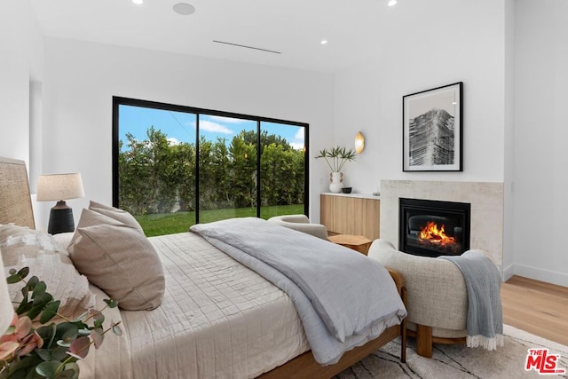 bedroom with a premium fireplace, access to exterior, and hardwood / wood-style floors