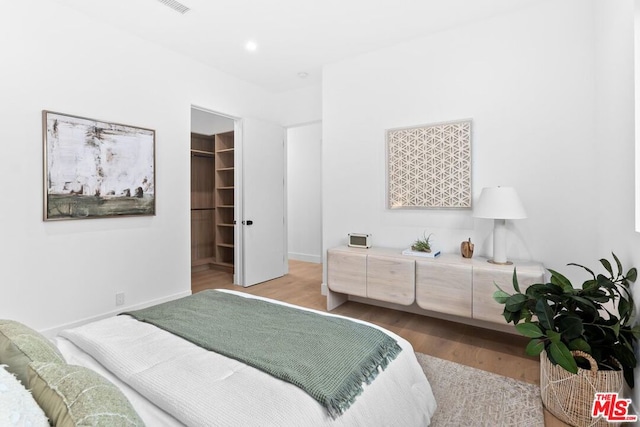 bedroom featuring a spacious closet, light hardwood / wood-style floors, and a closet