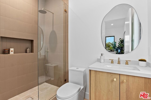 bathroom with vanity, tiled shower, and toilet