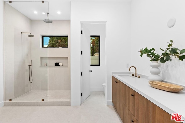 bathroom featuring vanity, a tile shower, and toilet