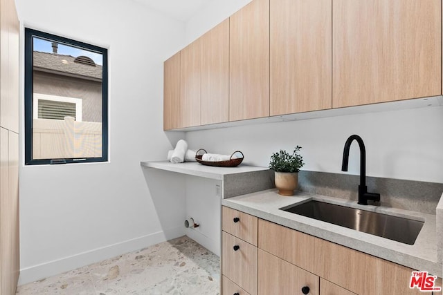 clothes washing area with sink and cabinets