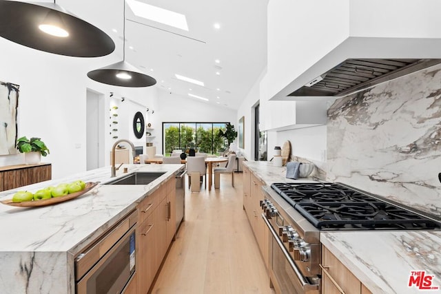 kitchen with sink, premium range hood, hanging light fixtures, stainless steel appliances, and light stone counters