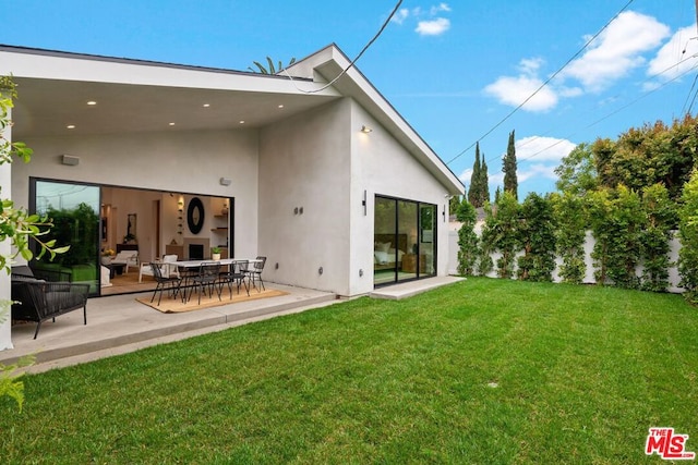 rear view of property featuring a lawn, a fireplace, and a patio area