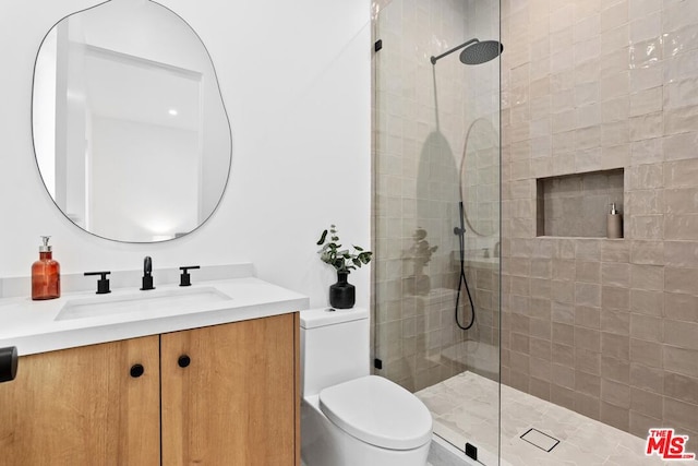 bathroom with vanity, toilet, and tiled shower