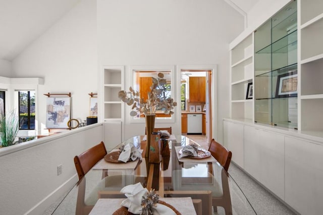 dining area with built in shelves and high vaulted ceiling