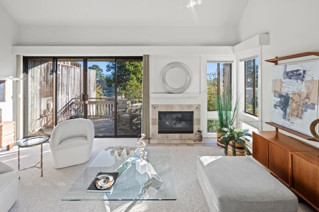 carpeted living room featuring a tile fireplace and vaulted ceiling