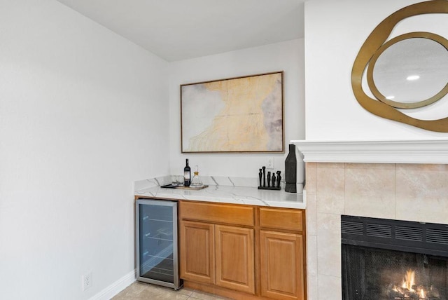 bar with a fireplace, beverage cooler, and light tile patterned flooring