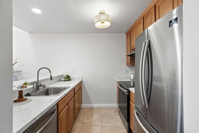 kitchen with light tile patterned floors, appliances with stainless steel finishes, sink, and light stone counters