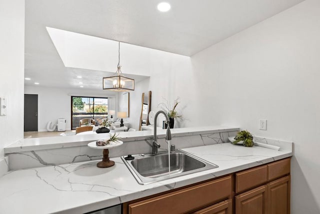 kitchen featuring hanging light fixtures, a notable chandelier, sink, and light stone counters