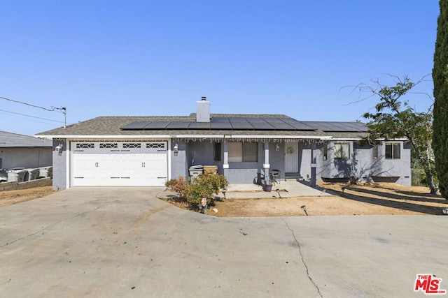 view of front of home with solar panels, covered porch, and a garage