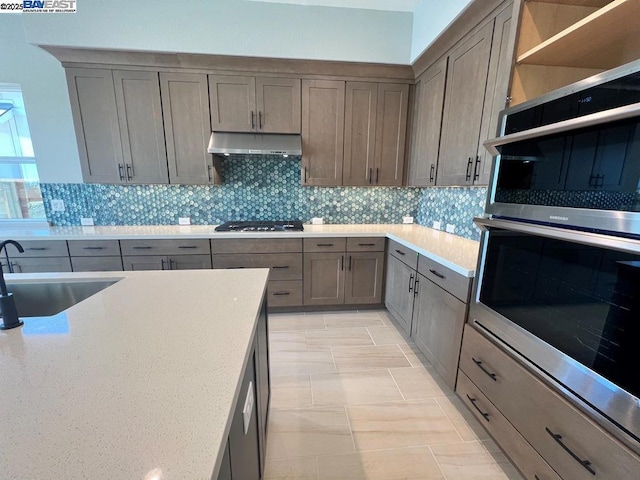 kitchen featuring decorative backsplash, sink, appliances with stainless steel finishes, and light tile patterned floors