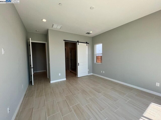 unfurnished bedroom with a spacious closet and a barn door