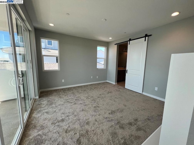 unfurnished bedroom featuring carpet floors and a barn door