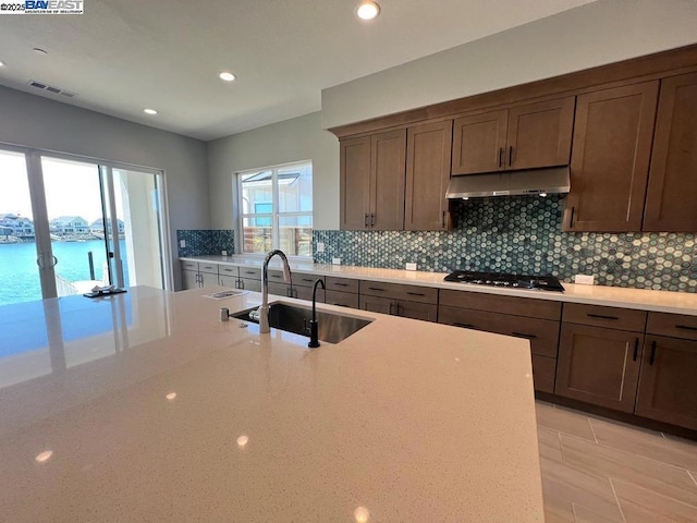 kitchen featuring a water view, stainless steel gas cooktop, sink, and a healthy amount of sunlight