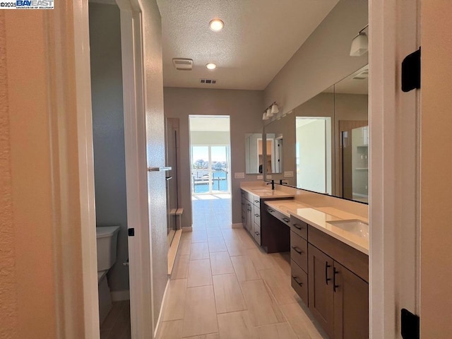 bathroom with a textured ceiling, toilet, and vanity