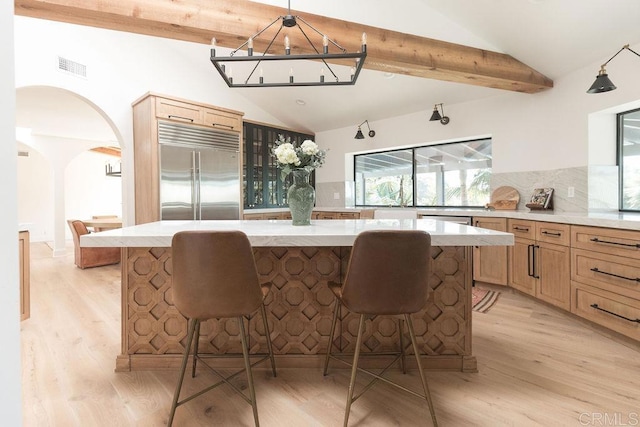 kitchen with light hardwood / wood-style flooring, built in fridge, tasteful backsplash, and a center island