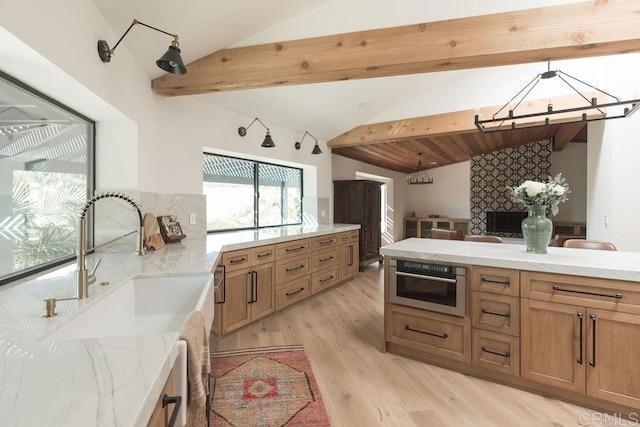 kitchen featuring stainless steel oven, tasteful backsplash, lofted ceiling with beams, light wood finished floors, and hanging light fixtures