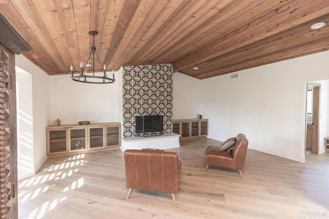 living room with a fireplace, light wood-style floors, vaulted ceiling with beams, wood ceiling, and a notable chandelier