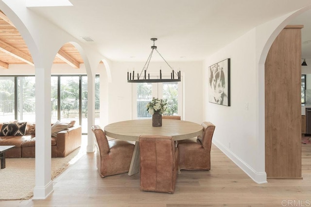 dining space featuring visible vents, light wood finished floors, baseboards, and beam ceiling